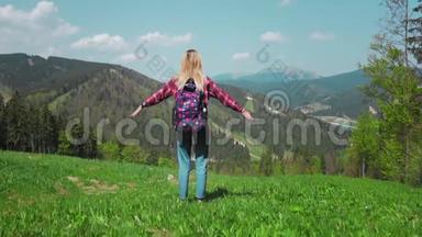 一个年轻的高加索女人带着背包和太阳镜<strong>站在山顶</strong>上举起双手。 概念